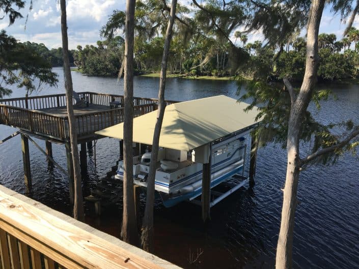 Boat dock on a serene river, featuring a covered boat and lush surrounding trees.