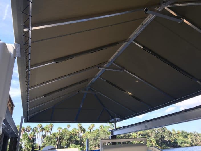 Retractable awning with blue sky and palm trees in the background, providing outdoor shade.