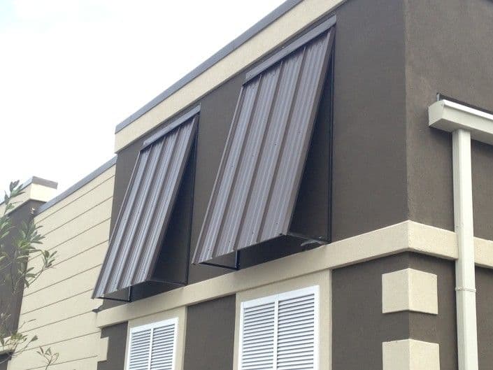 Exterior view of building with metal awnings installed above windows for sun protection.