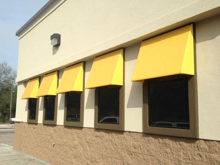 Yellow awnings above windows on a commercial building exterior.