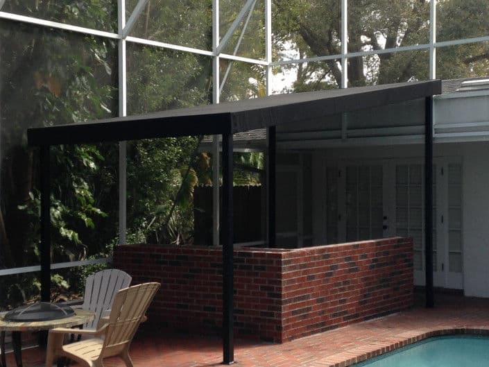 Poolside patio cover with brick wall and outdoor seating in a screened enclosure.