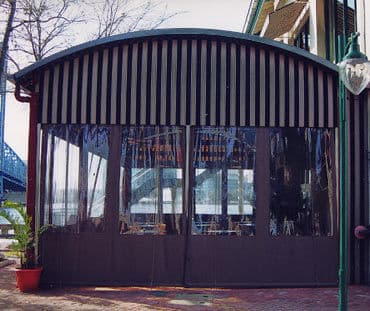 Exterior view of a modern restaurant with a curved roof and large glass windows.