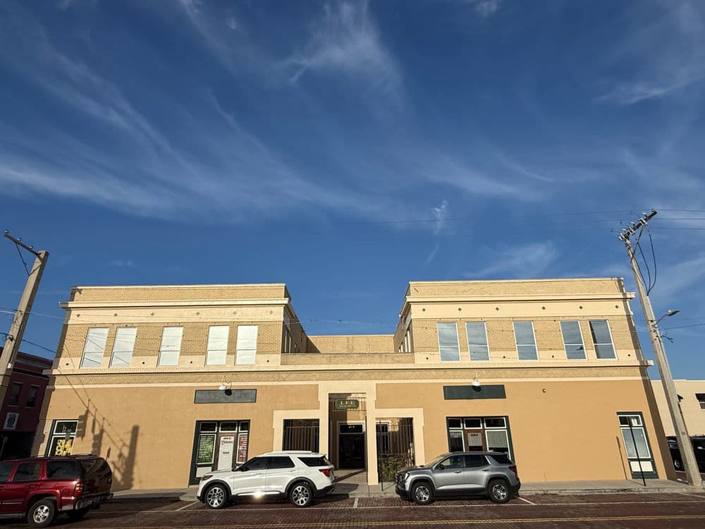 Historic building with green awnings and cloudy sky, showcasing classic architectural design.